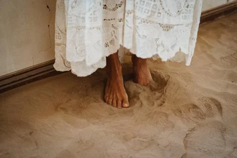 Barefooted bride standing in sand with white wedding Stock Photos