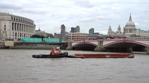 A barge being pushed by a tug along the River Thames towards a bridge in London. Stock Footage 80453362