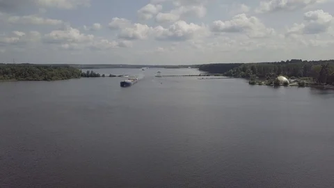 A barge floats along a canal of water on the shore of a large forest. Stock Footage 124166399
