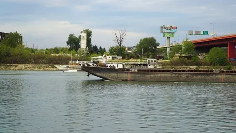 Barge i tug boat floating on wide river, ruined ship in the background. Stock Footage 80786761