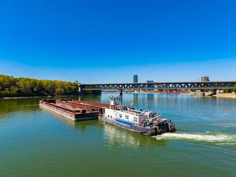 Barge moving under a bridge on a river in a bright day with clear blue sky Stock Photos