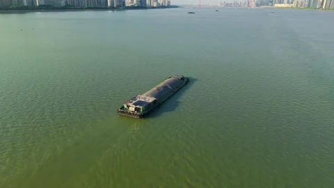 Barge navigating calm waters with city skyline in the background during a sunny Stock Footage 310117409