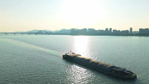 Barge sailing through urban waters with city skyline in the background on a Stock Footage 310117464
