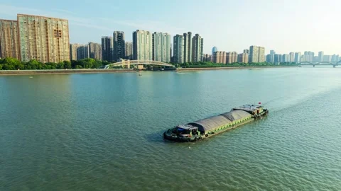 Barge sailing through urban waters with city skyline in the background on a Stock Footage 311557979