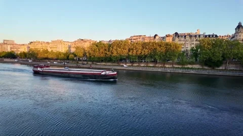 Barge travels down river in paris with buildings and trees lining shore dur.. Stock Footage 337703235