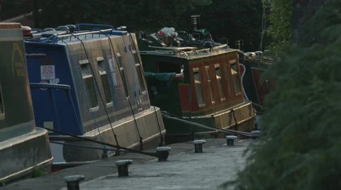 Barges on the Birmingham Canal System. A cyclists passes through frame at dusk. Stock Footage