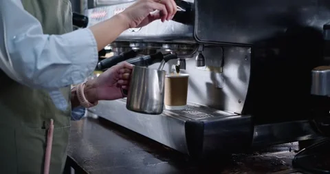Barista is activating espresso machine, pulling shot, steaming and pouring milk Stock Footage 344671274
