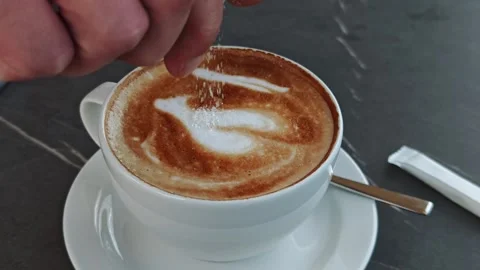 Barista adding sugar to cappuccino with latte art Vidéo 315356129