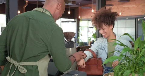 Barista and customer at counter checking watch and paying for coffee using POS, Stock Footage 343366828