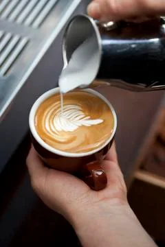 A barista decorating milk froth with a floral pattern Stock Photos