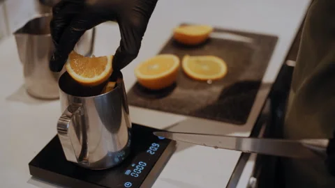 Barista Hand Cuts Orange and Measures Segments in Metal Cup on Scales Stock Footage 307586873