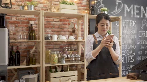 Barista laughing while chatting on cellphone Video stock 131688169