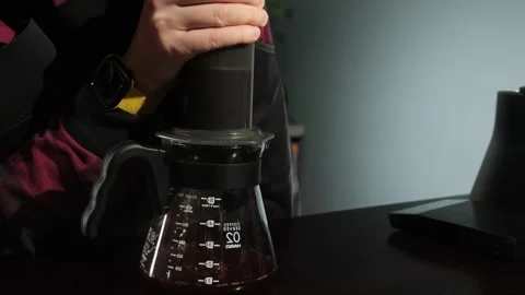 Barista lets brewed coffee drip into transparent jug holding pourover Stock Footage 306608332
