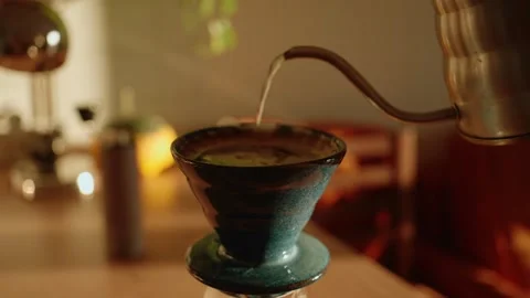 Barista making pour over coffee by pouring hot water from gooseneck kettle into Vidéo 346277573