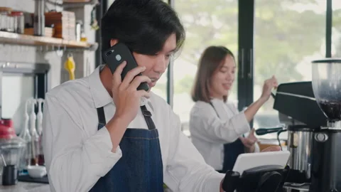 Barista man coffee maker receive phone call and record pre order to computer in Video stock 171697598