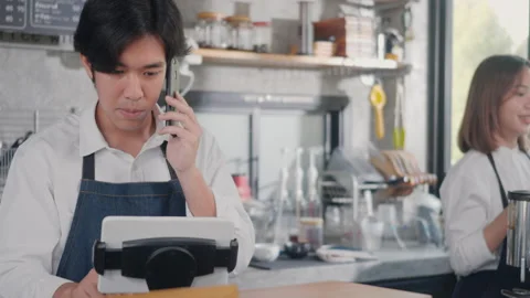 Barista man coffee maker receive phone call and record pre order to computer in Video stock 181309767