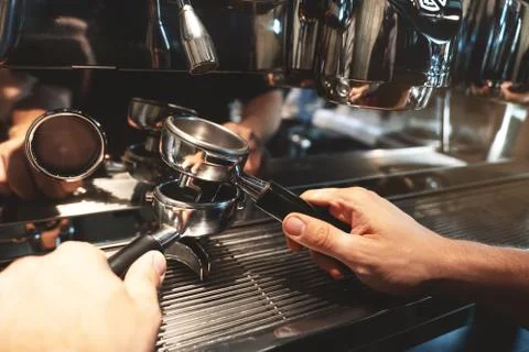 Barista man holding two coffee holders one above the other on coffee machine Stock Photos