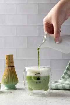 Barista pouring matcha latte into cute bear shaped glass in modern kitchen Stock Photos