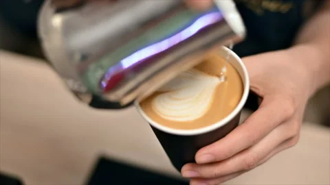 Barista pours milk with a pattern into a cup of coffee. Slow motion Stock Footage 201163399