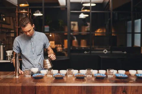 Barista preparing coffee tasting with rows of cups and beans Stock Photos