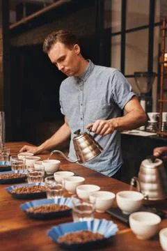 Barista preparing for a coffee tasting with rows of cups Stock Photos