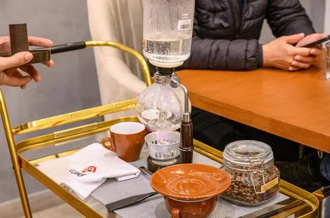 Barista preparing syphon coffee maker on golden serving cart Stock Photos