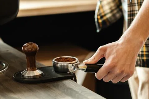 Barista presses ground coffee using tamper. Professional barista working make Stock Photos