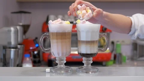 Barista putting marshmallows on two milkshakes at the counter of a restaurant 스톡 동영상 106372299