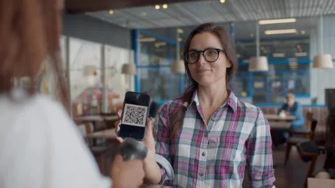 Barista scanning QR code in customer smartphone at counter in cafeteria. Stock-Fotos