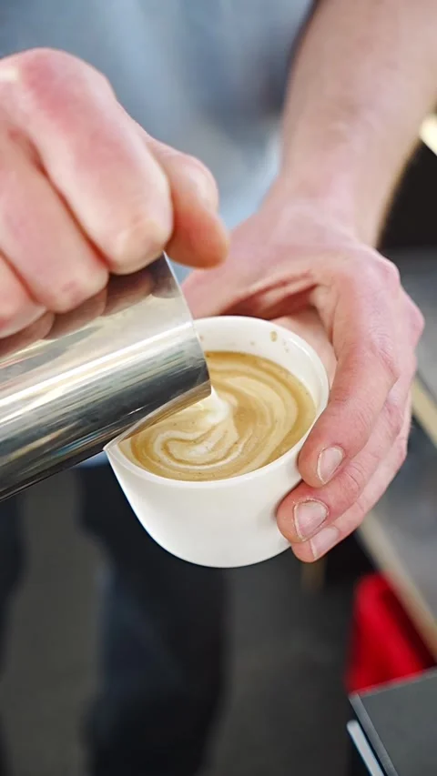 Barista skillfully pours steamed milk into a cup Stock Footage 345538862