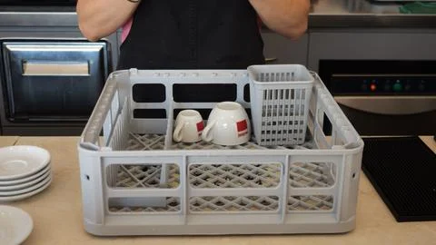 Barista stacking ceramic cups onto plastic tray, organizing workspace durin.. Stock Photos