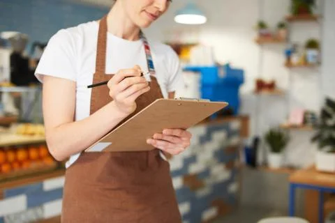 Barista standing while writing in the notepad. Stock Photos