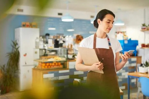 Barista standing while writing in the notepad. Stock Photos