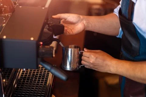Barista steaming milk in the pitcher with coffee machine for  preparing to ma Stock Photos