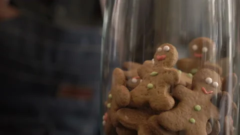 Barista take a gingerbread man cookie from a glass vase with tongs Video stock 133397358