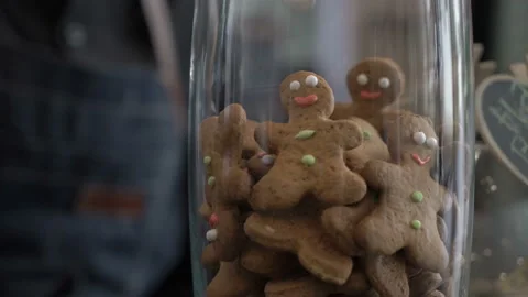 Barista take a gingerbread man cookie from a glass vase with tongs Stock Footage 133397399