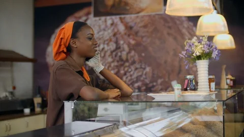 Barista talking on cell phone inside the counter in coffee shop Stock Footage 116753121