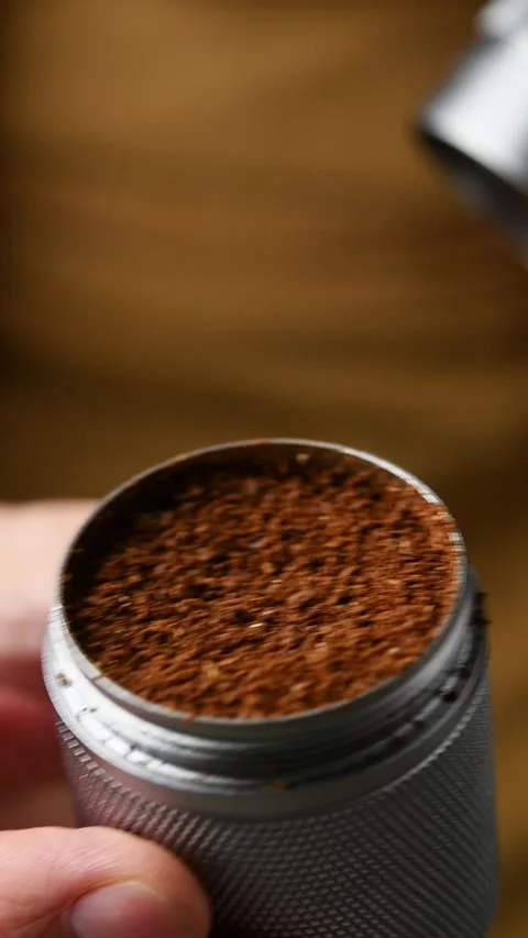 Barista twists off the bottom catch cup of a manual coffee grinder to reveal Stock Footage 346743693