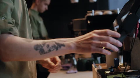 Barista using modern computer equipment and handing printed check to coworker Stockbeeldmateriaal 307550417