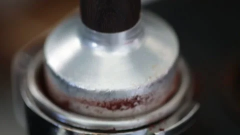 Barista using a tamper to press coffee grinds into portafilter Stock Footage 130574523