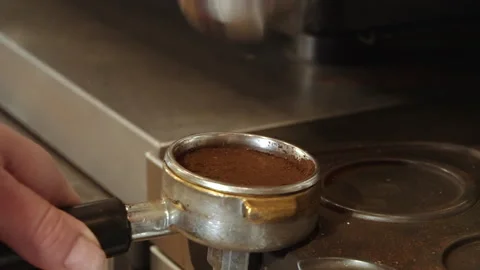 Barista using a tamper to press ground coffee into a portafilter Stock Footage 157980573