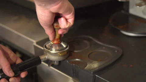 Barista using a tamper to press ground coffee into a portafilter Stock Footage 157980904