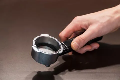 Barista using a tamper to press ground coffee into a portafilter. Stock Photos