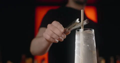 Barkeeper inserts the straw to the cocktail with ice cubes and soda water in Stock Footage 157480843