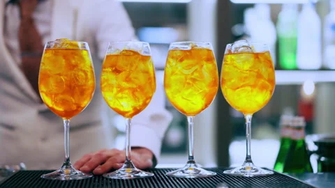 Barkeeper putting black drinking straws into the glasses with Aperol Spritz 動画素材 345501898