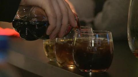 Barman adding coca cola into whisky. Waitress taking glasses away. Close Up. Vidéo 86921539