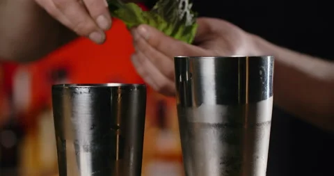Barman adds fresh mint leaf to the opened shaker, making of the cocktail with Stock Footage 156403971
