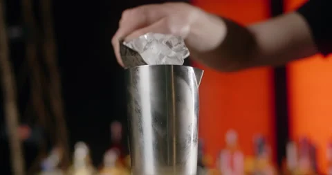 Barman adds ice cubes to the shaker in slow motion, bartender mixes cocktails on Stock Footage 156598892