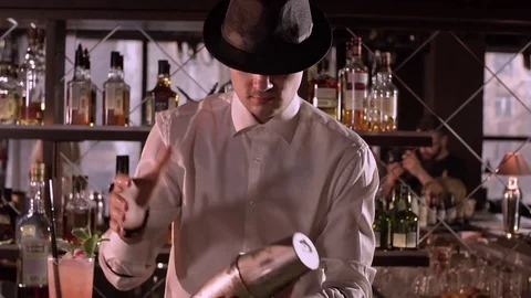 Barman in a black hat beautifully opens a shaker with a cocktail close-up slow Stock Footage 76721527