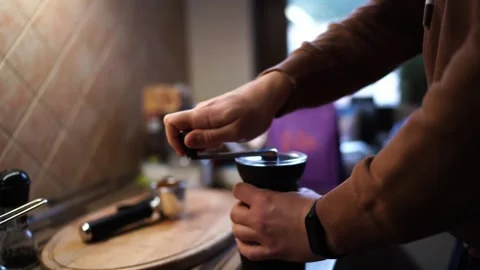 Barman grinds coffee beans on a manual coffee grinder on the table Stock Footage 280448642